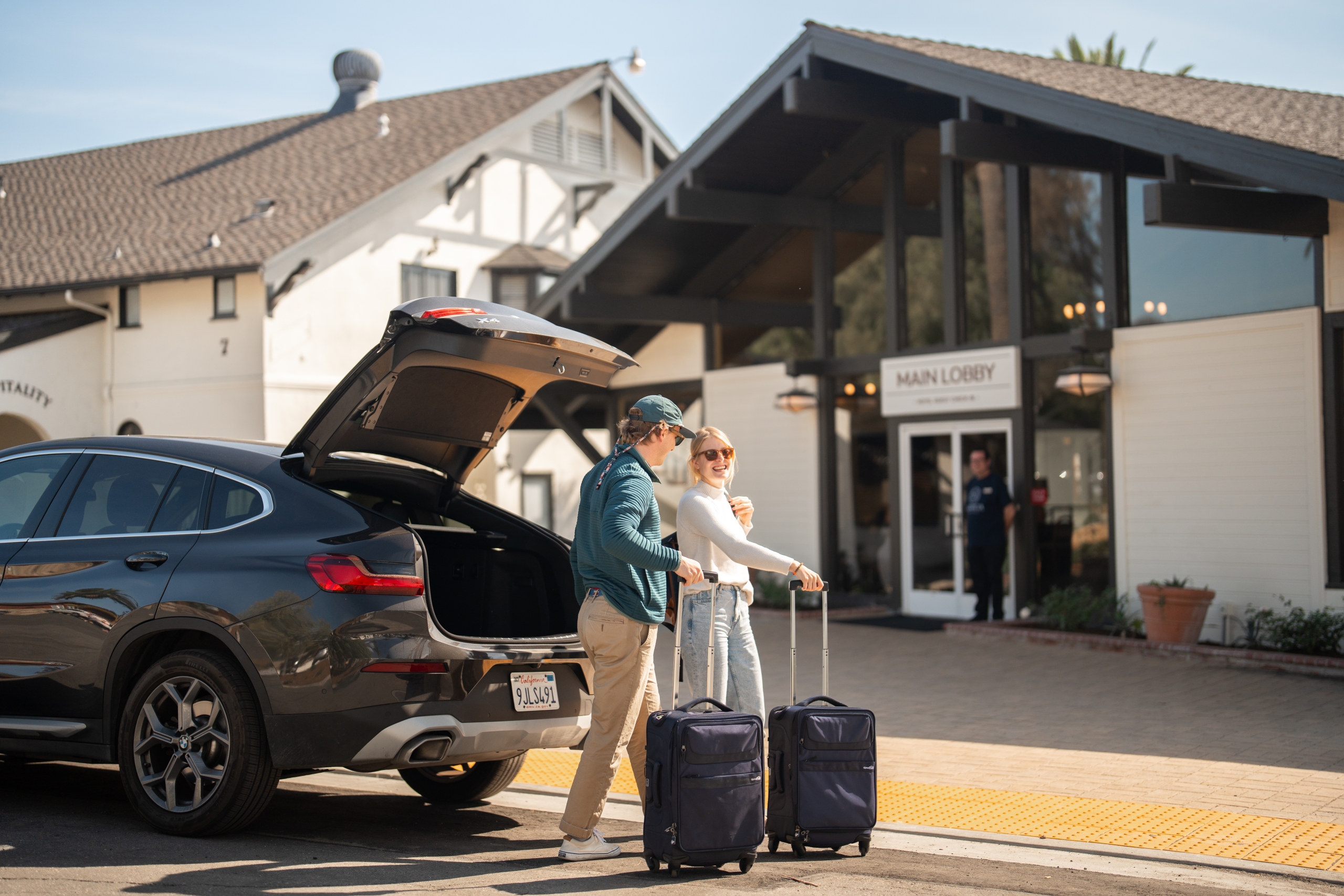 A couple removing their suitcases from their car.